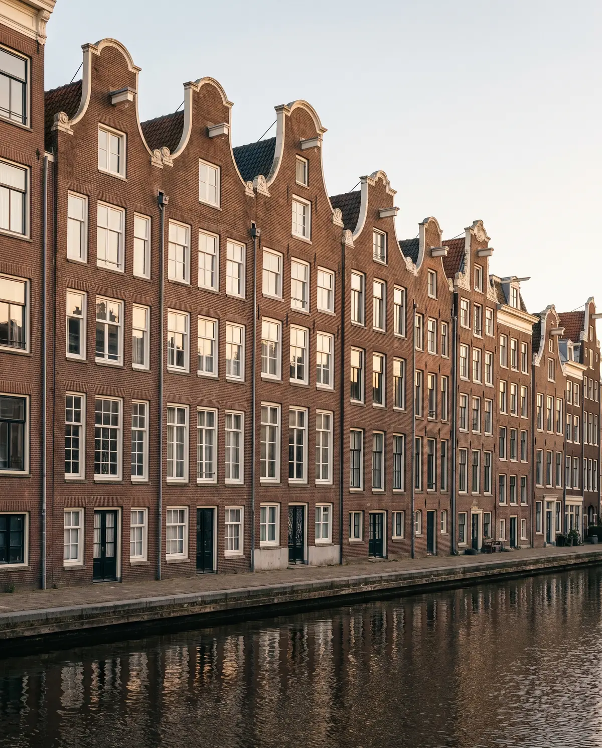 Hollandse waterkant met grachtenpanden, een modern kantoorgebouw, bedrijfshallen en een molen